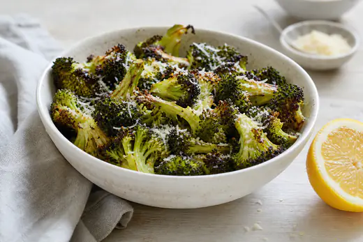 Geroosterde broccoliroosjes met bruine randjes en geraspte Parmezaanse kaas in een schaal
