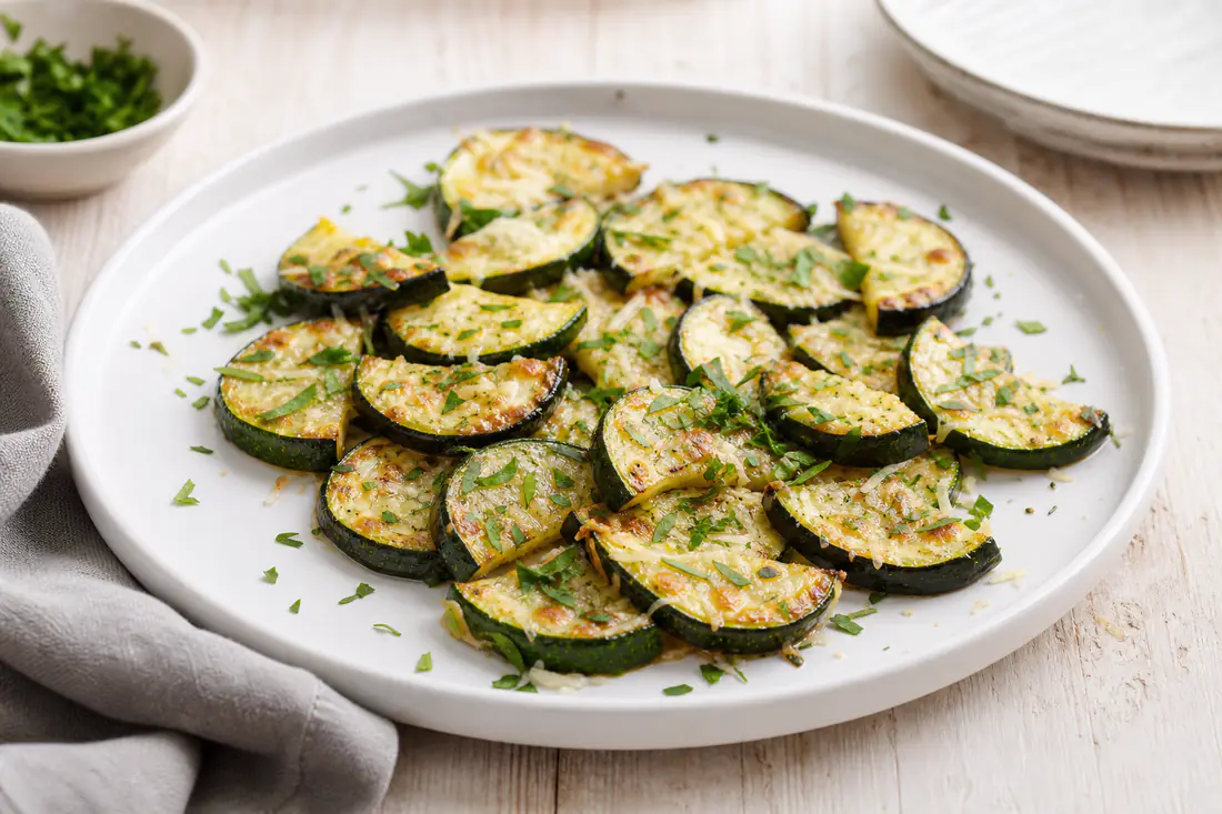 Geroosterde halve maantjes courgette met gesmolten Parmezaanse kaas en peterselie op een bord