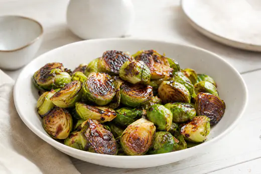 Gehalveerde geroosterde spruitjes met donkere randjes en balsamico in een witte schaal