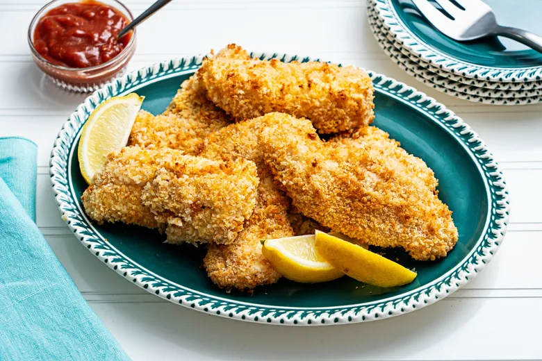 Perfect gebakken visfilets in de airfryer geserveerd met een schijfje citroen.